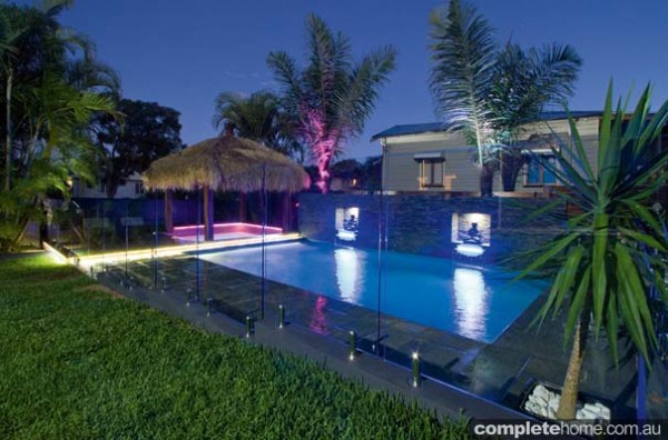 A tropical resort-style pool lit with LED lights from Malibu Pools.