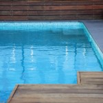 Corner of a pool with wooden platform and wooden wall