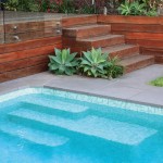 Corner of a pool with wooden stairs and succulent plants