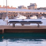 Close up of outdoor furniture next to a pool with a view of buildings behind across a river