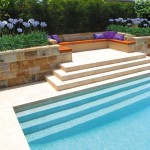 Modern pool corner with sandstone wall and flowers