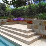 An elevated outdoor spot with cushions next to a modern pool