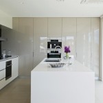 A simple modern kitchen with a white island and bright flowers