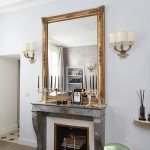A gold-framed mirror sitting atop a stone fireplace is a throwback to ’40s perfection