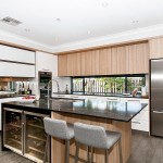 Simple modern kitchen with black marble island and two tall chairs