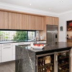 A modern kitchen with black marble island and a mini bar underneath