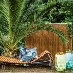 Adjustable day bed  and multi-function screen  in Natural. Designed  by Mark Snyders.  houseofbamboo.com.au Hex tables in Minty  Powder Blue and Pale Yellow, Oasis outdoor cushion in Palm Trees  and South Pacific.  escapetoparadise.com.au